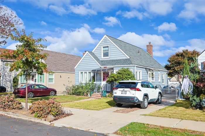 Bungalow-style house featuring a front lawn, a chimney, and a shingled roof