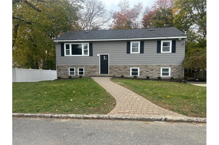 Split foyer home featuring stone siding and a shingled roof