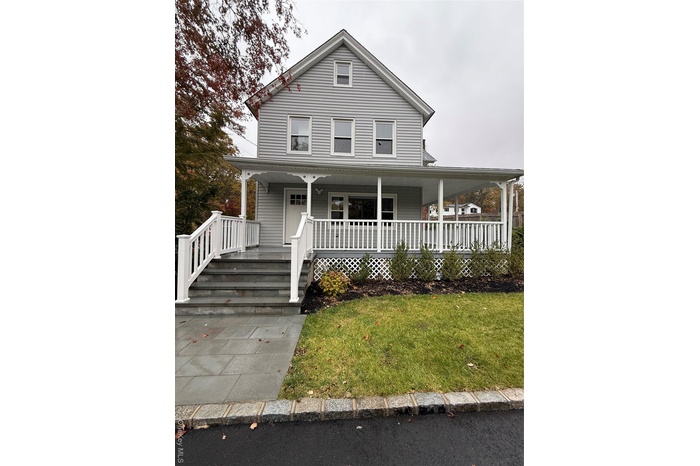 Farmhouse inspired home with covered porch and a front lawn