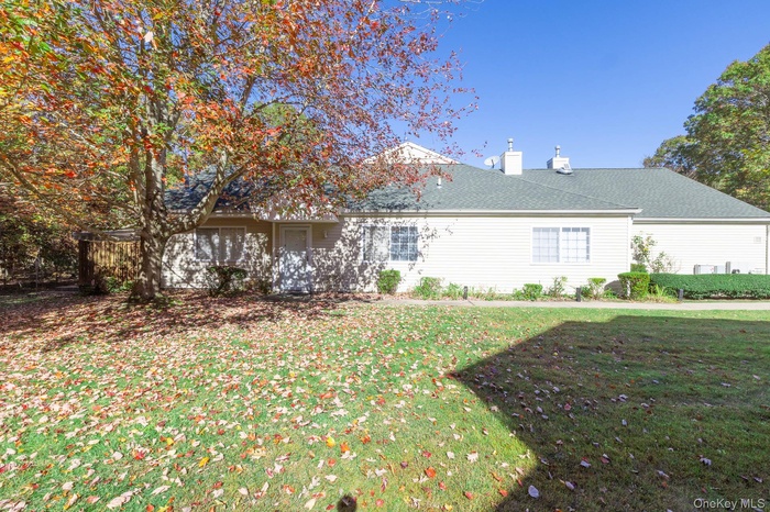 Back of property with a yard, a chimney, and roof with shingles