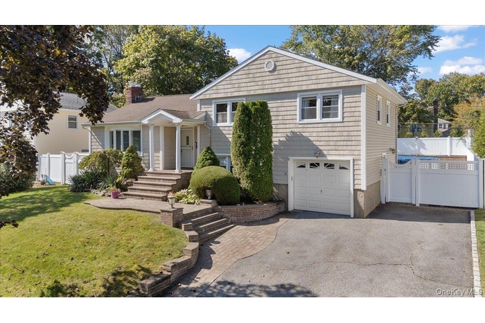 View of front of home featuring a garage, asphalt driveway, and a chimney