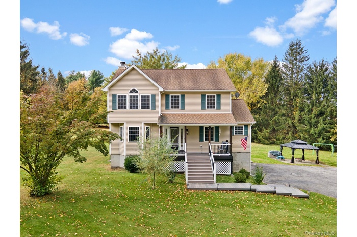 View of front of house featuring a front lawn, stairway, a chimney, and a shingled roof
