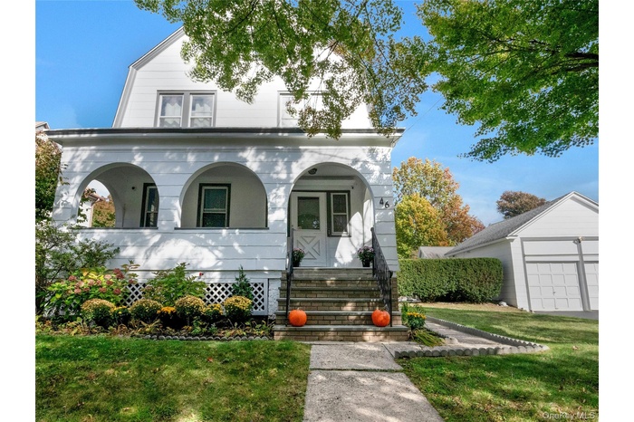 View of front of house featuring a front yard, a porch, an outbuilding, and a garage