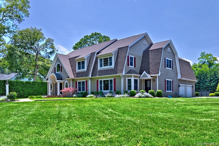 View of front of house with a gambrel roof, a front lawn, and roof with shingles