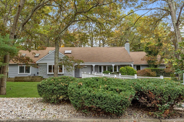 Ranch-style house with covered porch, a chimney, a shingled roof, and a front lawn