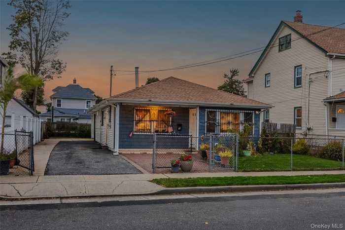 View of front facade with a gate, a fenced front yard, and a shingled roof