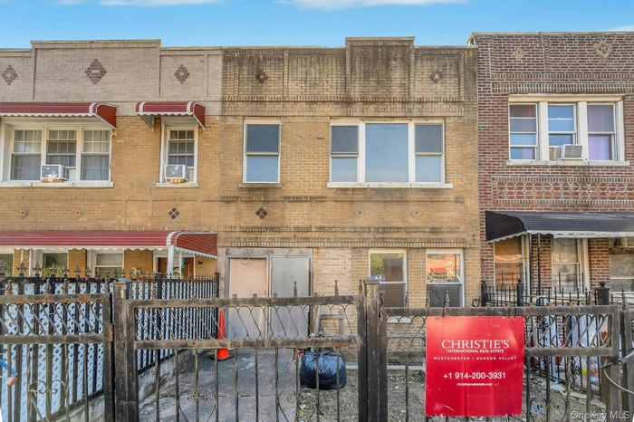 Rear view of house with a gate, brick siding, and a fenced front yard