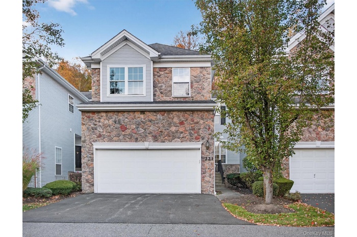 View of front of house featuring stone siding, driveway, and a 2-car garage