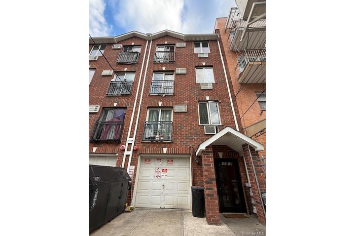View of building exterior featuring a garage, concrete driveway, and cooling unit