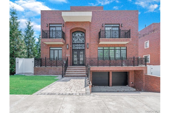 View of front of home featuring brick siding, a balcony, driveway, and a gate