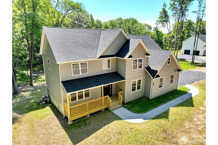 View of front of home with a shingled roof, a front lawn, and a deck