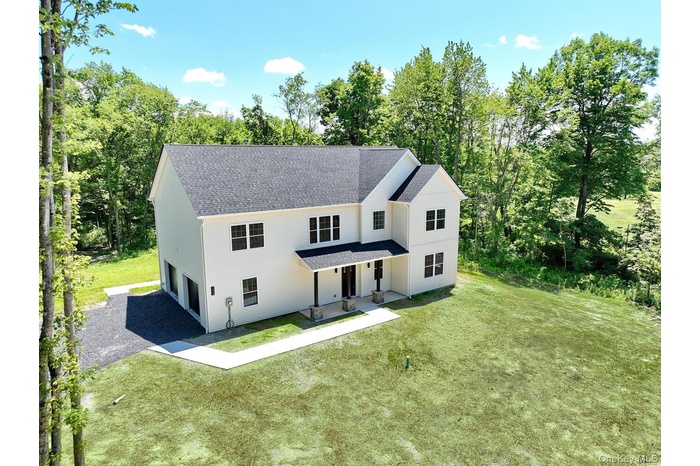 View of front of house with roof with shingles, a porch, a front yard, and driveway