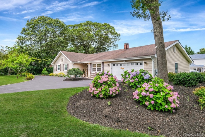 Single story home with a chimney, an attached garage, a front yard, roof with shingles, and asphalt driveway