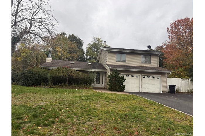 Traditional-style home featuring driveway, a chimney, and an attached garage