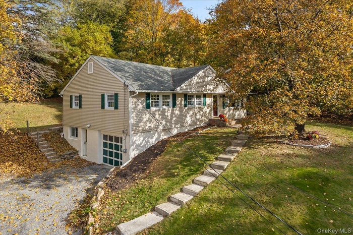 A gorgeous approach with mature landscaping, steps to the front and rear of home as well as a lower level entrance.