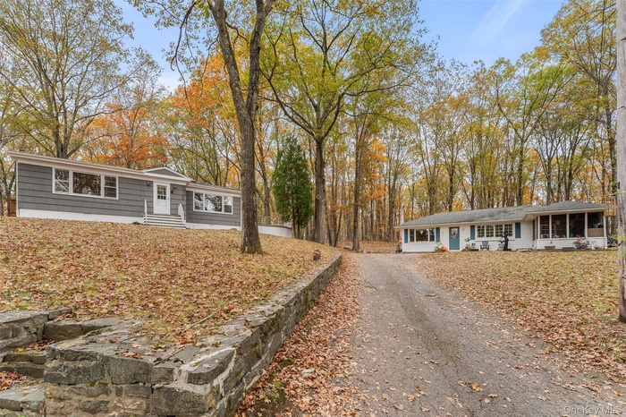 Ranch-style house featuring driveway, entry steps, and a sunroom