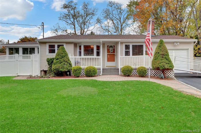 Ranch-style house with a porch, a shingled roof, an attached garage, and a chimney