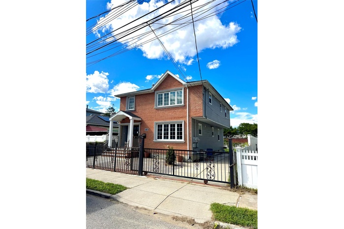 View of front facade featuring a fenced front yard, brick siding, and a gate