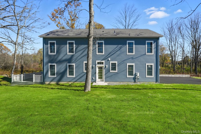 Rear view of property featuring a yard and a wooden deck