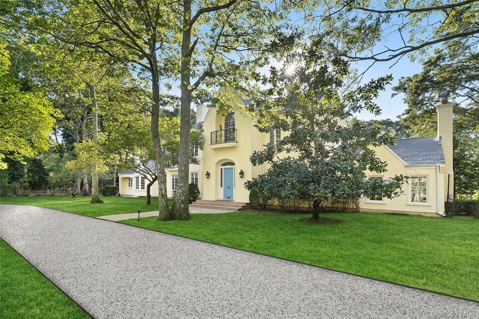 View of front of house with a chimney, a front lawn, stucco siding, and a balcony