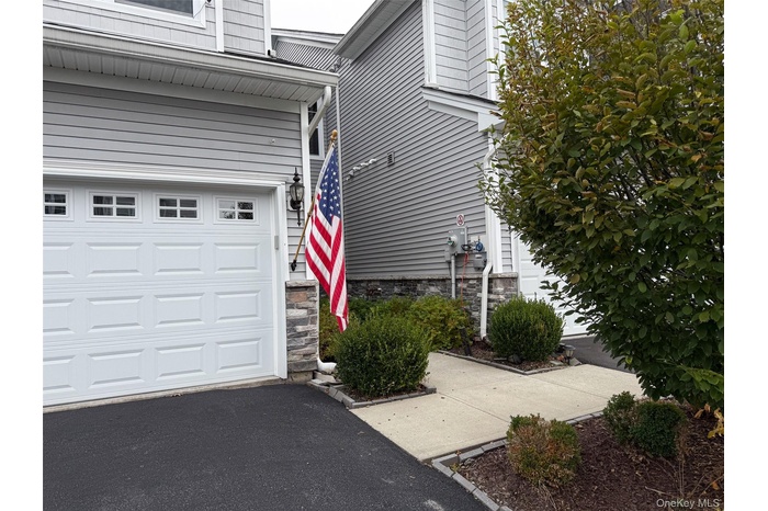 Doorway to property featuring stone siding, driveway, and an attached garage