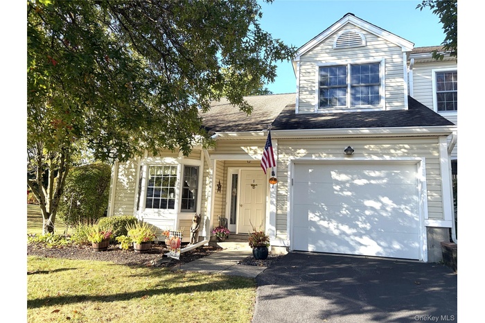 End unit condo with a driveway, garage, and a front yard
