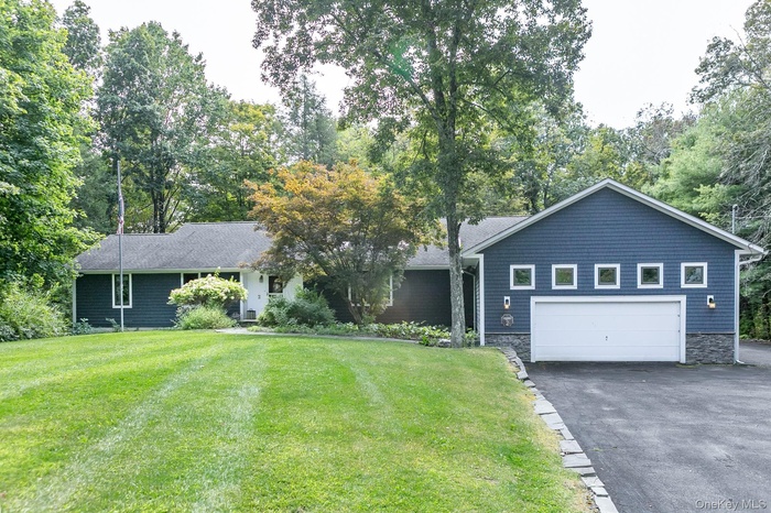 Single story home featuring driveway, a front yard, and an attached garage