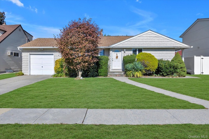 View of front of house with driveway, a garage, and a shingled roof