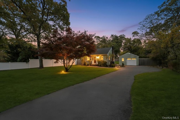 View of front of house with a detached garage, an outdoor structure, and asphalt driveway