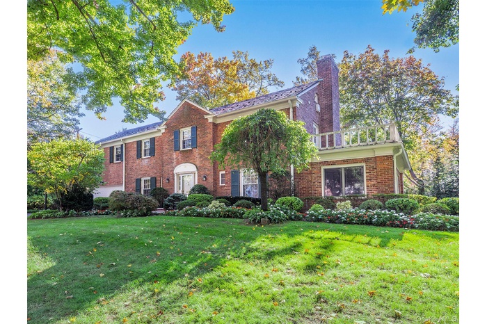 View of front of house featuring a front yard, a chimney, and brick siding