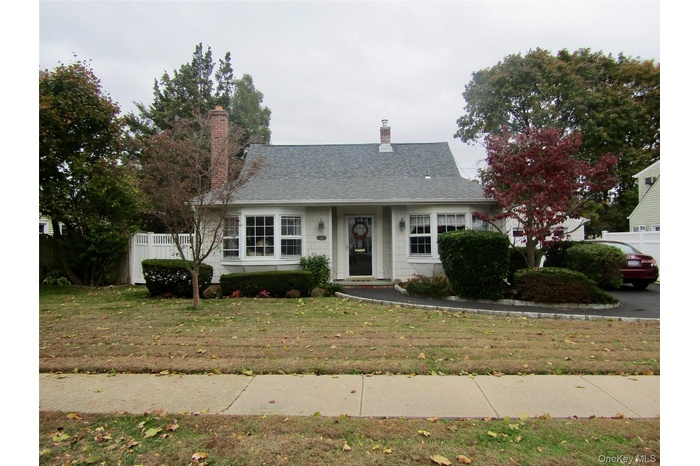 View of front of property featuring a chimney and roof with shingles