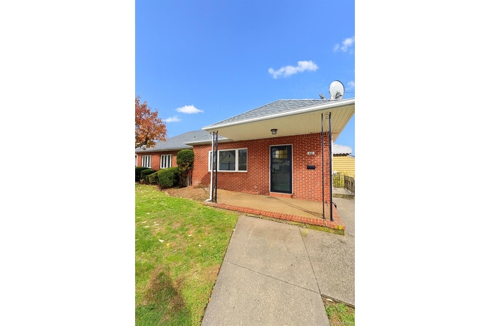 View of front of house featuring a front yard, brick siding, covered porch, and a shingled roof