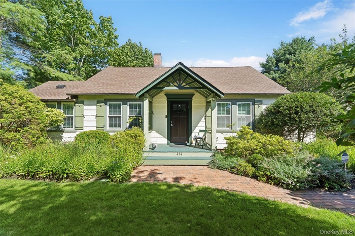 View of front of house with roof with shingles, a chimney, and a front lawn