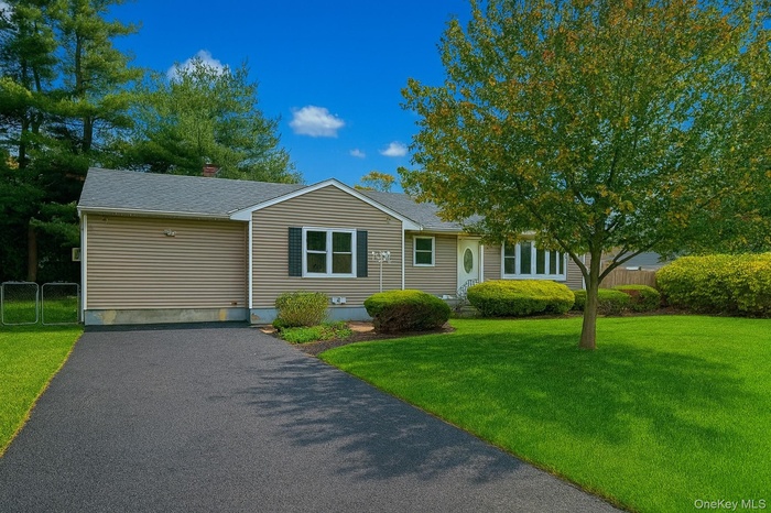 View of front of property with roof with shingles, a chimney, and asphalt driveway