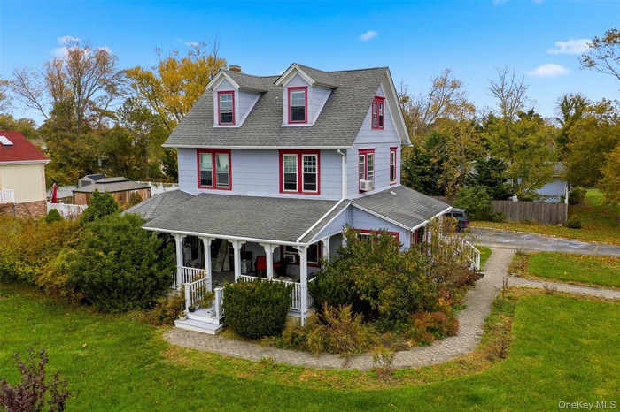 View of front facade featuring covered porch, roof with shingles, and a chimney