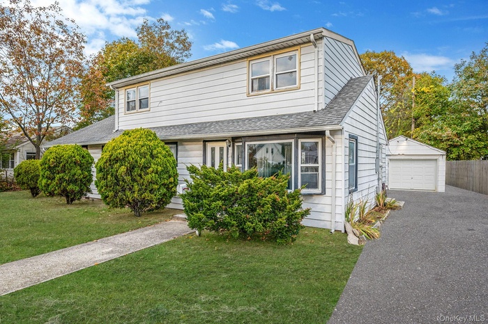 Traditional-style home with an outbuilding, roof with shingles, a detached garage, and asphalt driveway