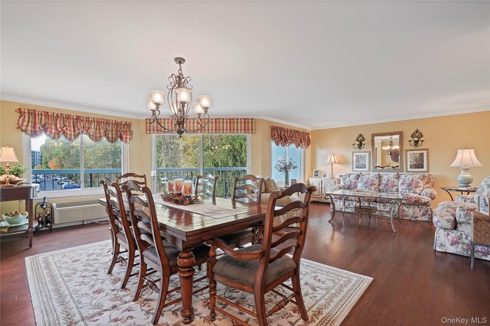 Dining room featuring ornamental molding, a chandelier, and dark wood-style flooring