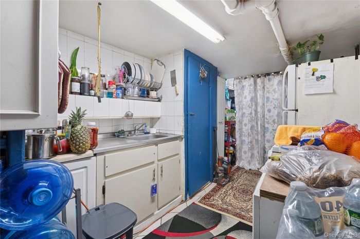 Kitchen featuring white cabinetry, stainless steel counters, and freestanding refrigerator