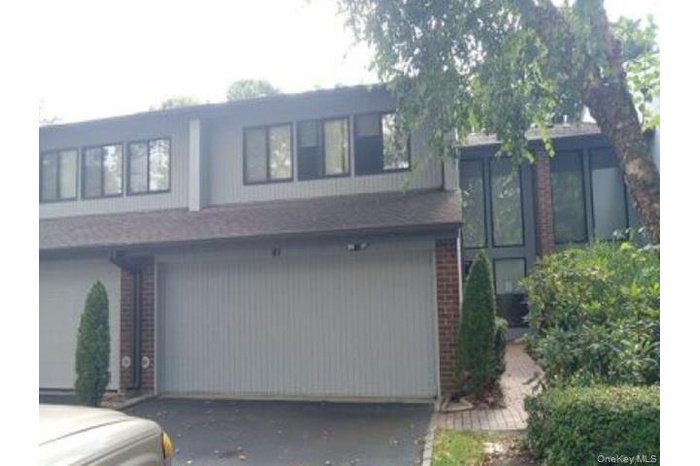 Tri-level home featuring driveway, a garage, and brick siding