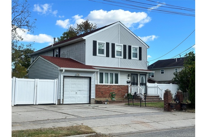 Traditional-style house featuring driveway, brick siding, and a garage
