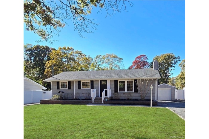 Ranch-style house with a chimney, a garage, an outdoor structure, and roof with shingles