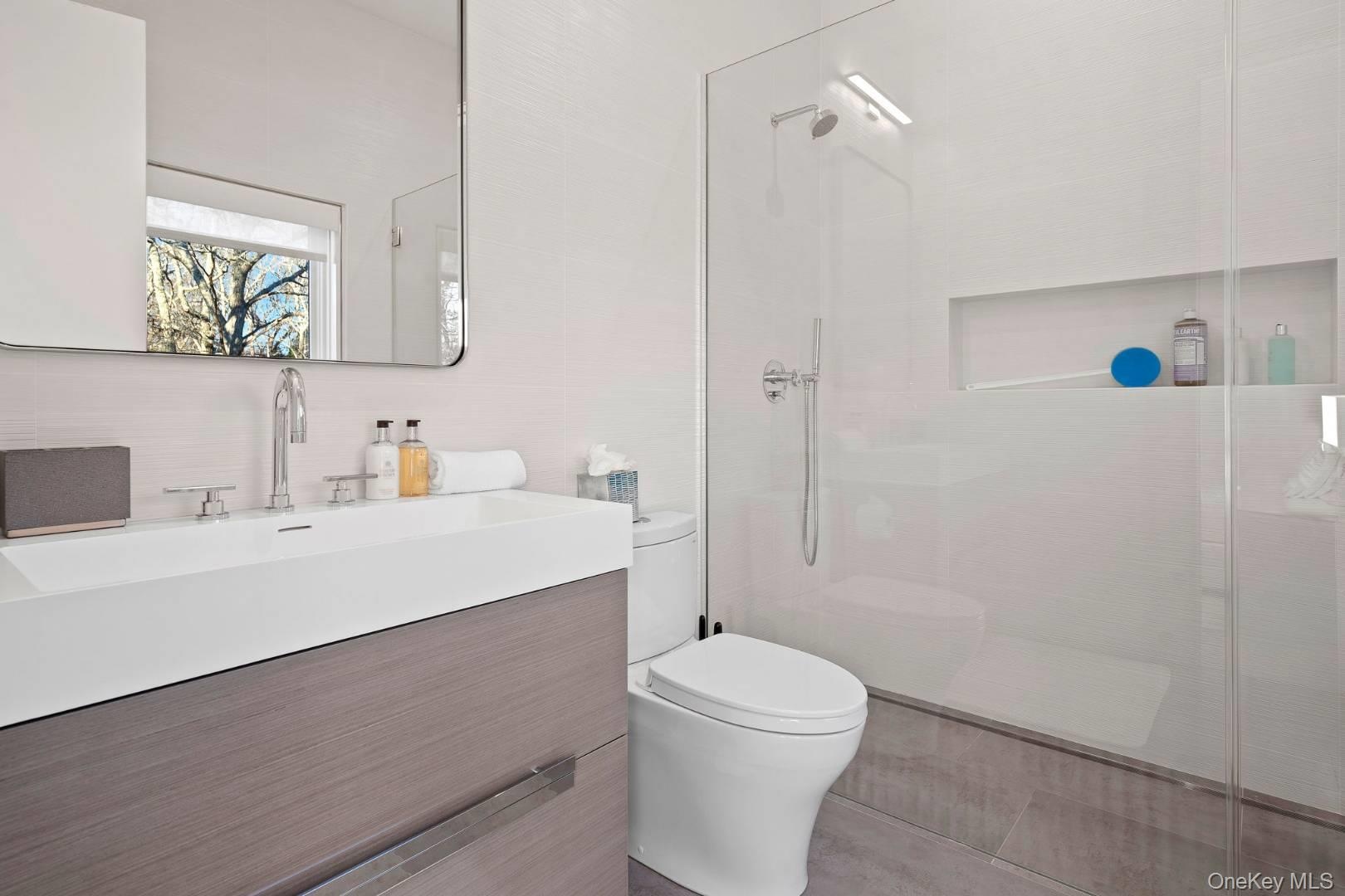 Bathroom with decorative backsplash, a tile shower, vanity, tile walls, and toilet