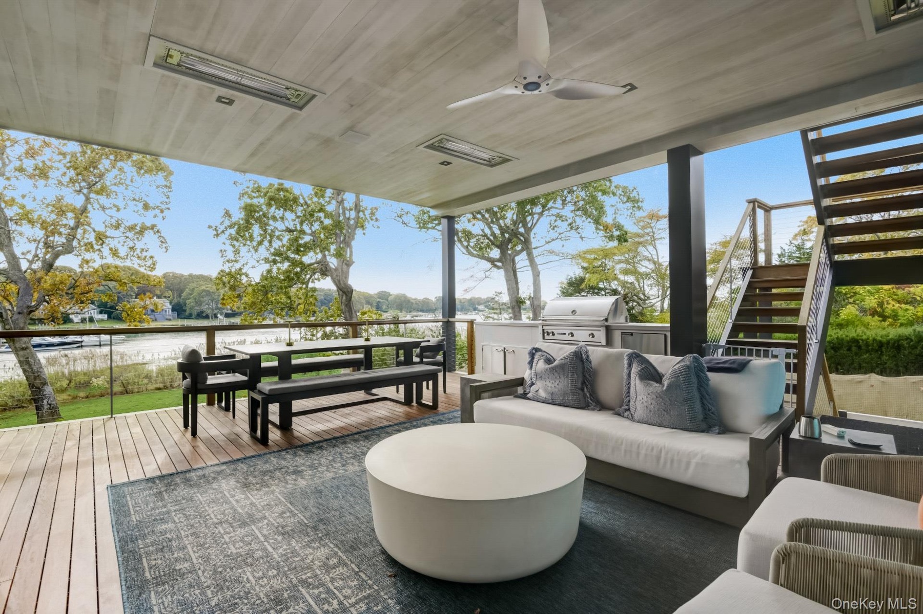 Deck with outdoor lounge area, a water view, ceiling fan, a grill, and exterior kitchen