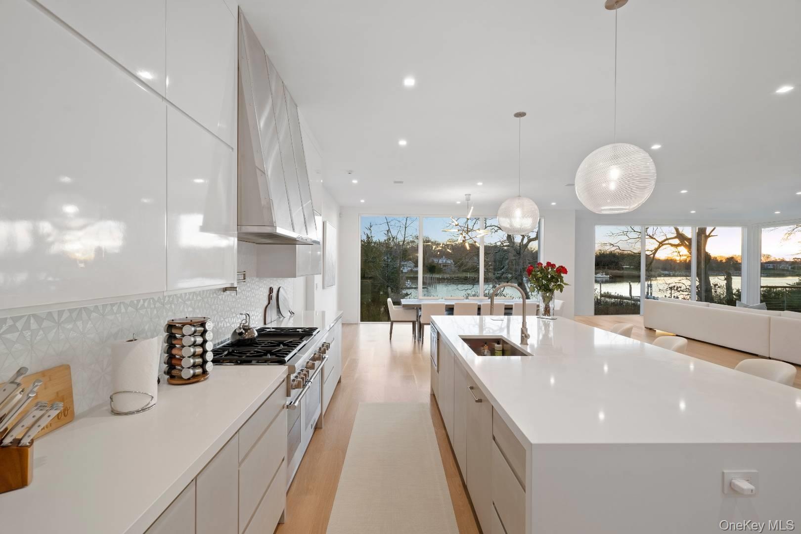 Kitchen featuring white cabinets, a healthy amount of sunlight, a spacious island, and sink