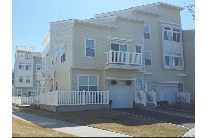 Townhome / multi-family property featuring driveway, a garage, and a balcony