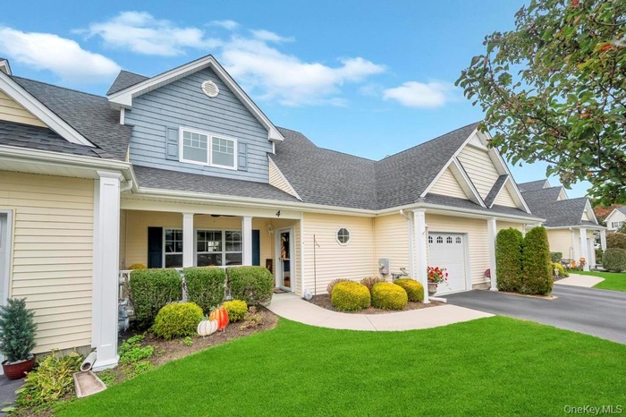 View of front of property featuring roof with shingles, a front yard, a porch, and driveway