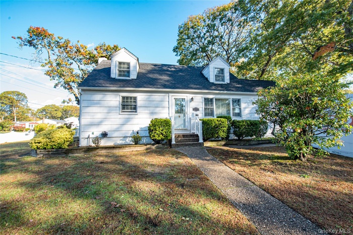 Cape cod home with a front yard and a shingled roof