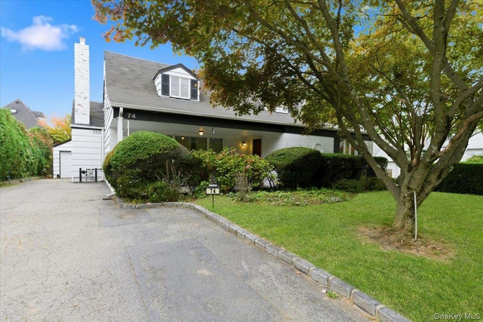 View of front facade featuring a front lawn, a chimney, a garage, stairs, and brick siding