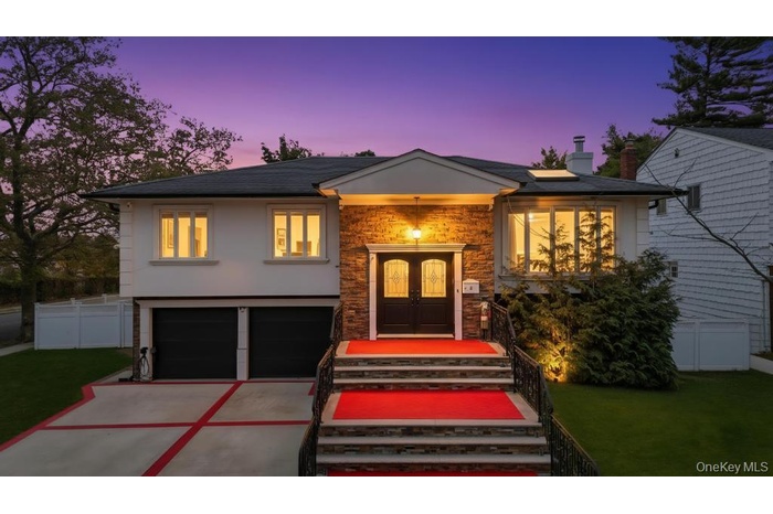 Raised ranch with concrete driveway, a garage, stone siding, french doors, and a chimney