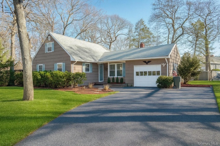 Staged using AI. View of front of home featuring a chimney, a garage, asphalt driveway, and a front yard